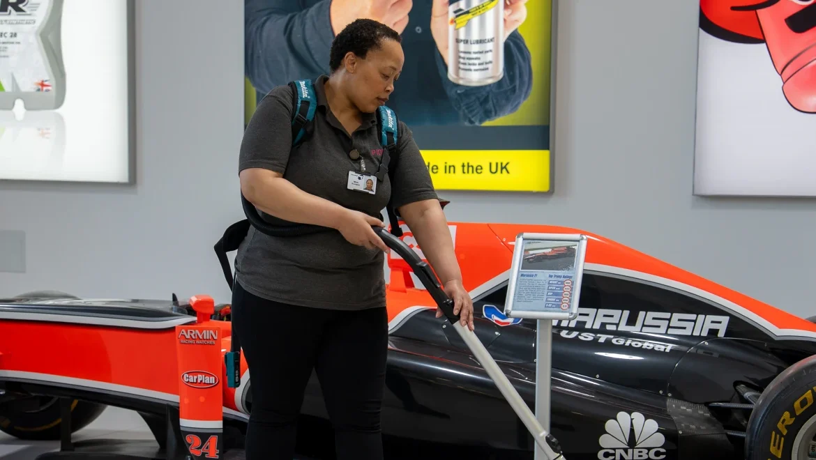 Commercial cleaning team cleaning Formula 1 car in reception area UK