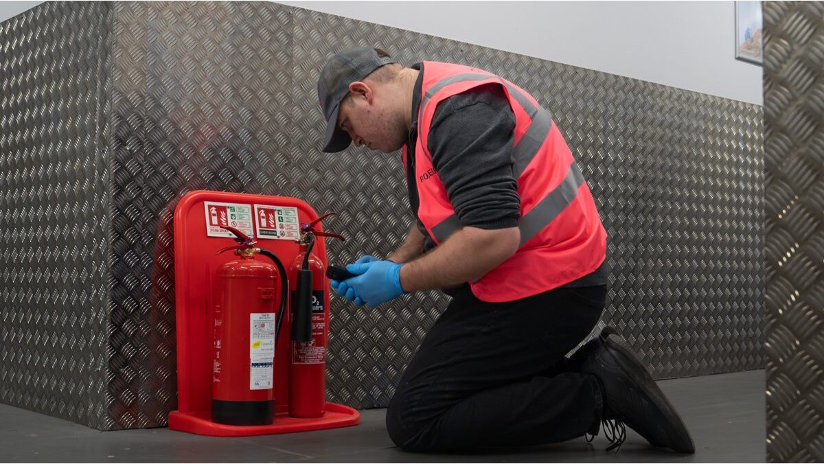Fire safety engineer testing fire extinguishers during routine compliance inspection