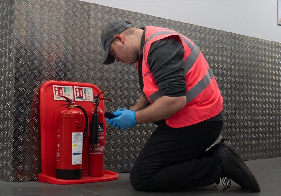 Fire safety engineer testing fire extinguishers during routine compliance inspection