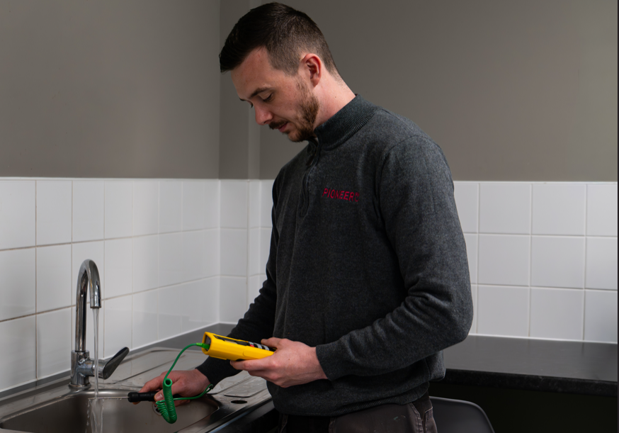 Fabric engineer carrying out temperature testing for legionella compliance in commercial building UK