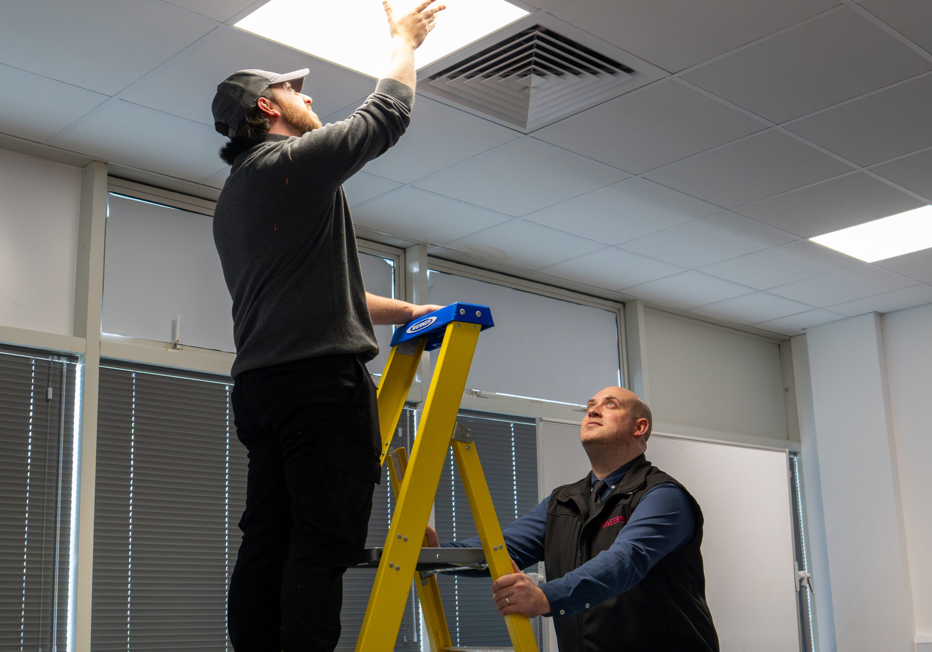 Engineer carrying out planned maintenance lighting inspection in a commercial building