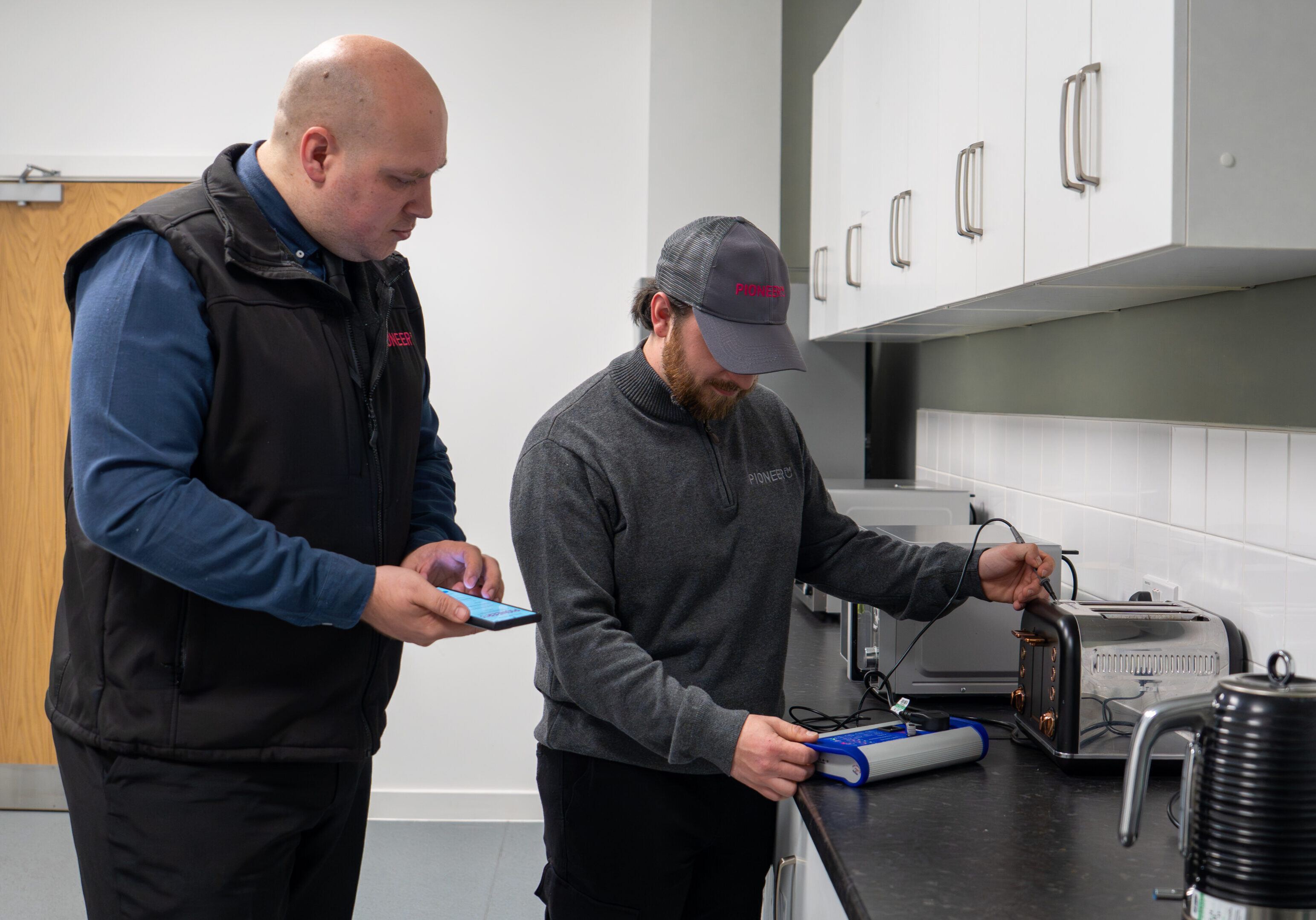 Commercial handyman engineers carrying out workplace maintenance in office kitchen UK